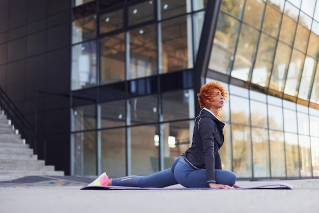 Jeune femme rousse européenne en vêtements sportifs faisant du fitness à l'extérieur