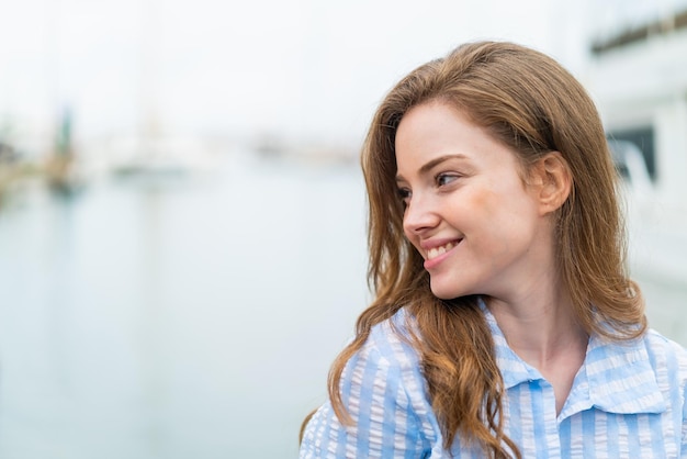 Jeune femme rousse à l'extérieur avec une expression heureuse