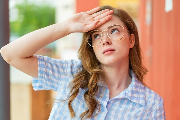 Photo jeune femme rousse à l'extérieur avec des lunettes et fatigué