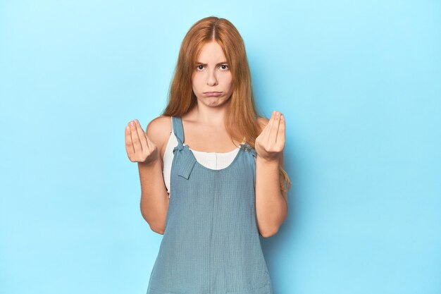 Jeune femme rousse sur fond bleu montrant qu'elle n'a pas d'argent