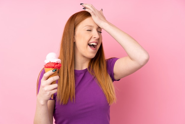 Photo jeune femme rousse avec une glace au cornet sur rose a réalisé quelque chose et a l'intention de la solution