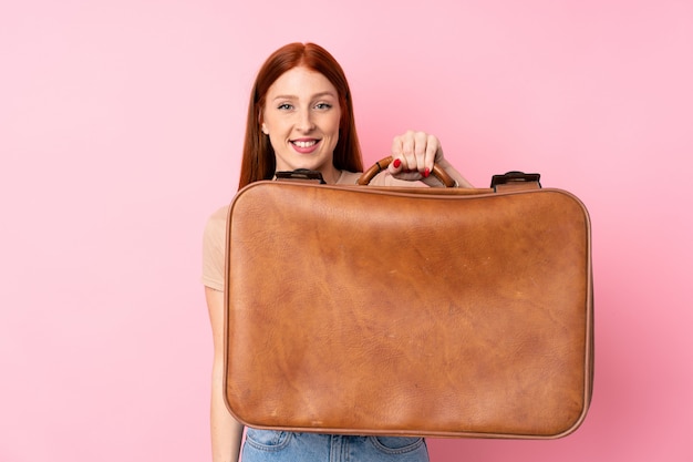 Jeune femme rousse sur isolé tenant une mallette vintage