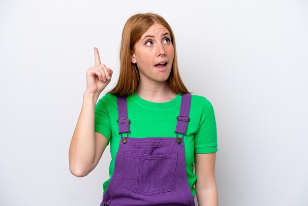 Jeune femme rousse isolée sur fond blanc ayant l'intention de réaliser la solution tout en levant un doigt