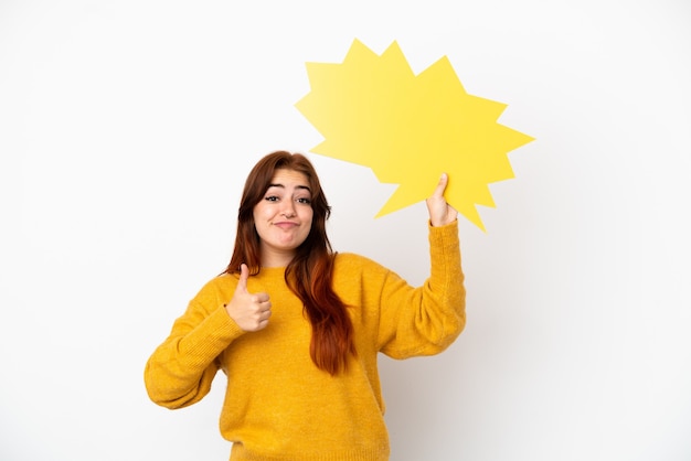 Jeune femme rousse isolée sur fond blanc tenant une bulle de dialogue vide avec le pouce vers le haut