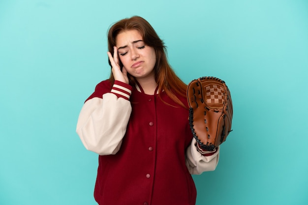 Jeune femme rousse jouant au baseball isolé sur fond bleu avec des maux de tête