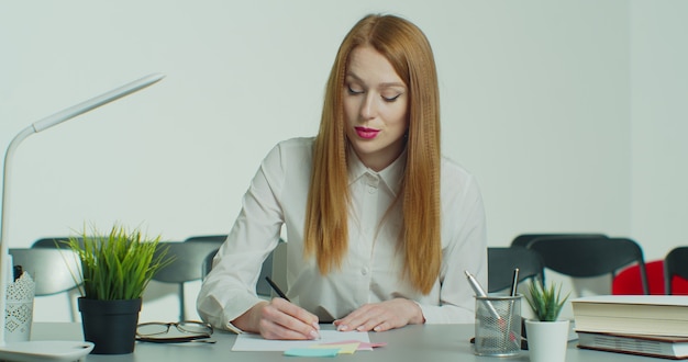 Jeune femme rousse à lunettes a une conférence téléphonique en ligne.