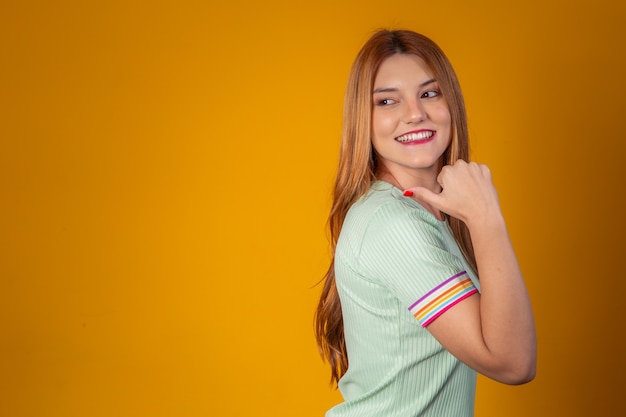 Jeune femme rousse pointant sur l'espace libre pour le texte sur fond jaune.