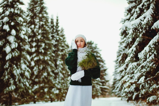 jeune femme rousse en pull vert, robe de mariée blanche marchant dans le parc d'hiver glacial. Noël