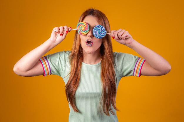 Jeune femme rousse avec des sucettes colorées lui bandant les yeux. concept de mode