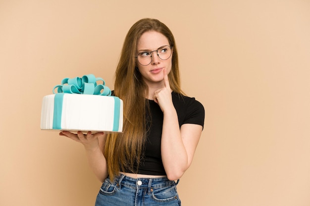 Jeune femme rousse tenant un gâteau sucré isolé découpé