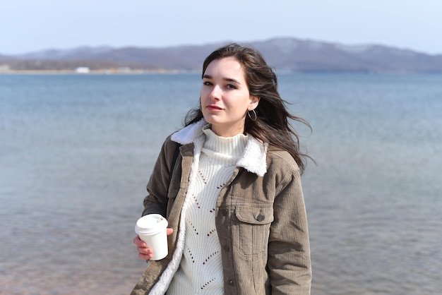 Jeune femme russe buvant du café contre la mer japonaise au printemps