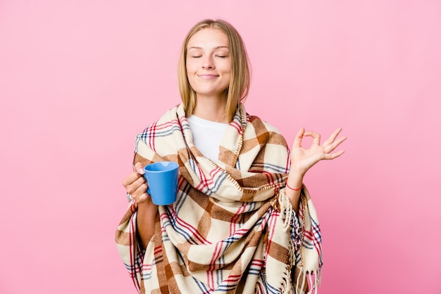 Jeune femme russe enveloppée dans une couverture de boire du café se détend après une dure journée de travail, elle effectue du yoga