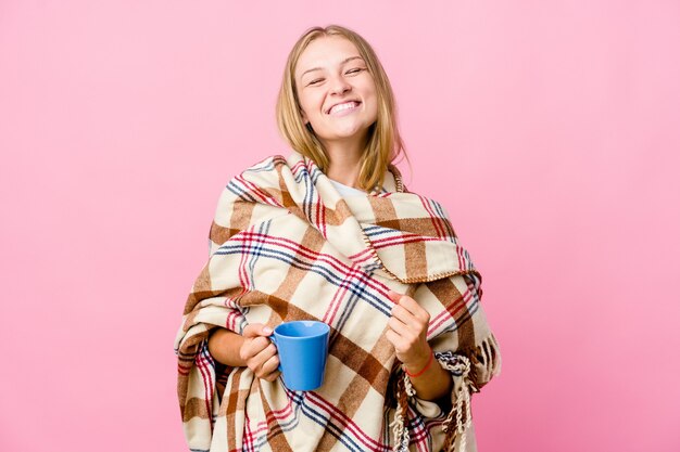 Jeune femme russe enveloppée dans une couverture buvant du café rit et ferme les yeux, se sent détendue et heureuse.