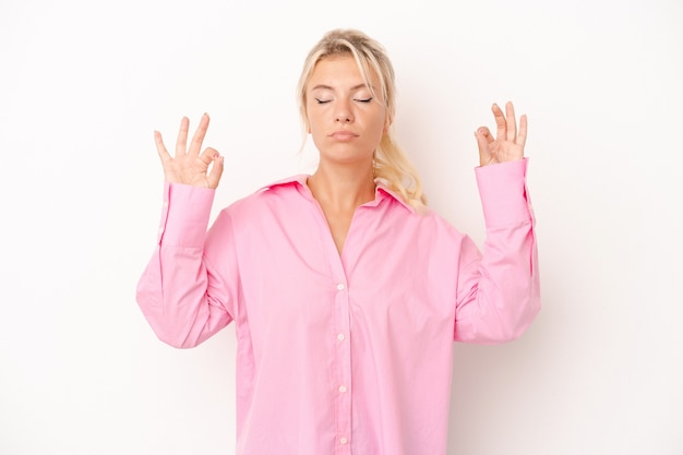 Jeune femme russe isolée sur fond blanc se détend après une dure journée de travail, elle fait du yoga.