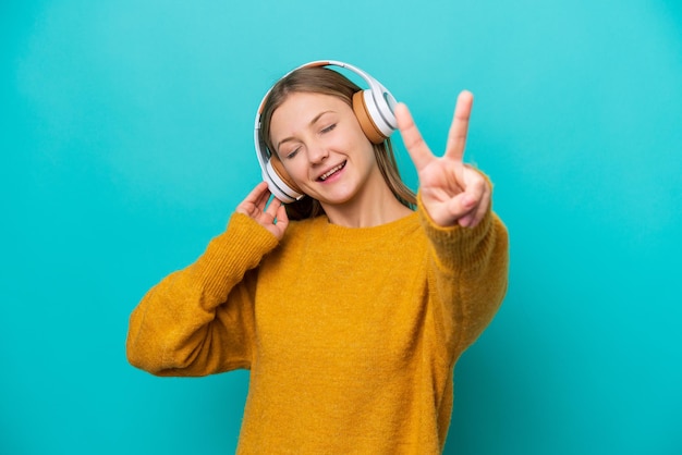 Jeune femme russe isolée sur fond bleu à l'écoute de la musique et du chant