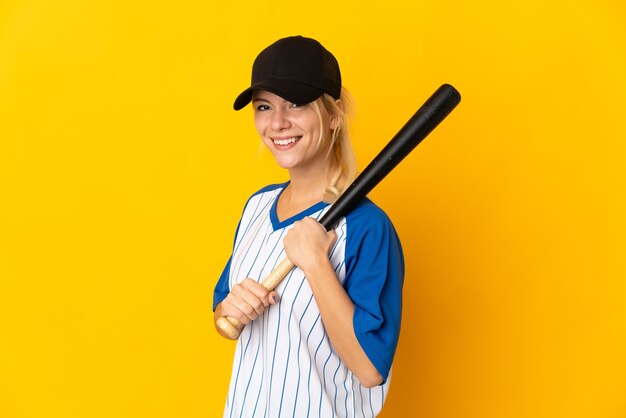 Jeune femme russe isolée sur fond jaune jouant au baseball