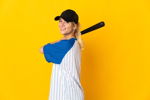 Jeune femme russe isolée sur fond jaune jouant au baseball