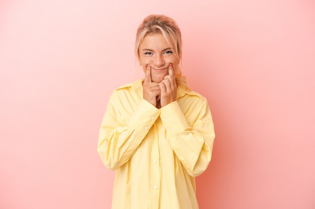 Jeune femme russe isolée sur fond rose doutant entre deux options.