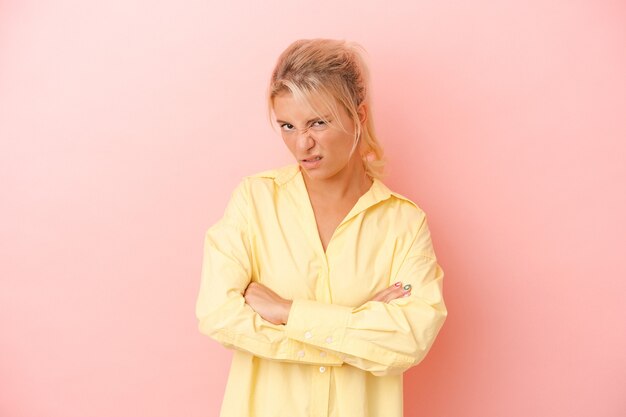 Jeune femme russe isolée sur fond rose malheureuse à la recherche à huis clos avec une expression sarcastique.