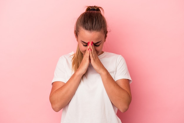 Jeune femme russe isolée sur fond rose priant, montrant sa dévotion, personne religieuse à la recherche d'une inspiration divine.