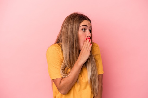 Jeune femme russe isolée sur fond rose réfléchie à la recherche d'un espace de copie couvrant la bouche avec la main.