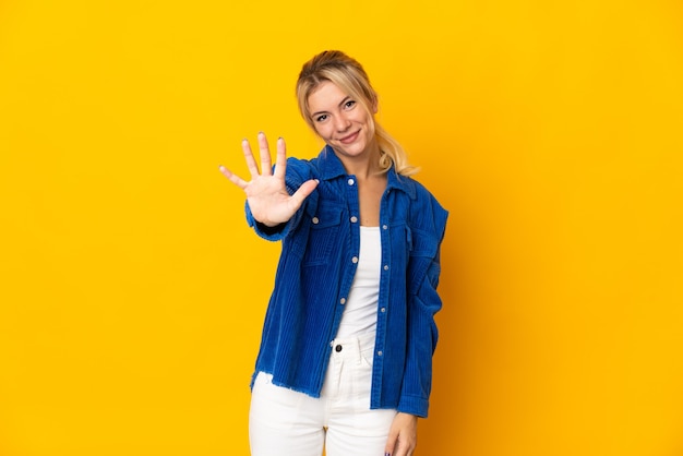 Jeune femme russe isolée sur mur jaune comptant cinq avec les doigts