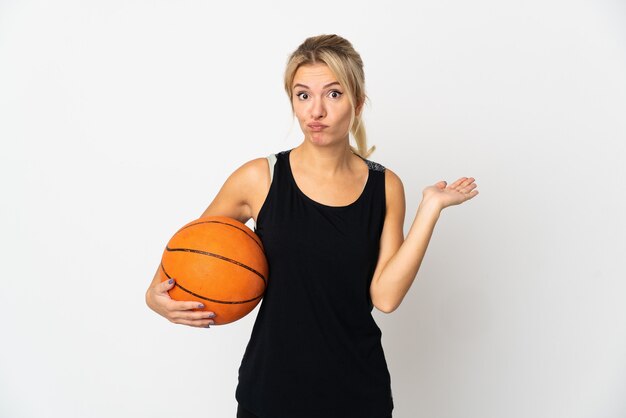 Jeune femme russe jouant au basket-ball isolé sur fond blanc ayant des doutes en levant les mains