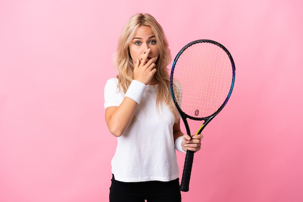 Jeune femme russe jouant au tennis isolé sur fond violet surpris et choqué tout en regardant à droite