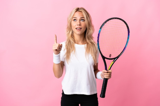 Jeune femme russe jouant au tennis isolé sur mur violet pointant vers le haut et surpris