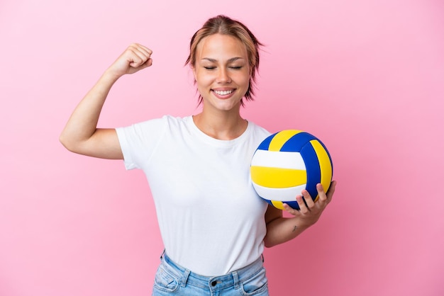 Jeune femme russe jouant au volley-ball isolé sur fond rose faisant un geste fort