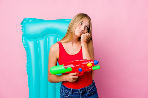 Jeune femme russe jouant avec un pistolet à eau avec un matelas pneumatique qui se sent triste et pensif, regardant l'espace de copie.