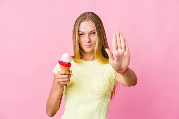 Jeune femme russe mangeant une glace debout isolé avec la main tendue montrant le panneau d'arrêt, vous empêchant.