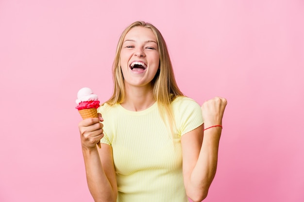 Jeune femme russe mangeant une glace isolée acclamant insouciant et excité. Concept de victoire.