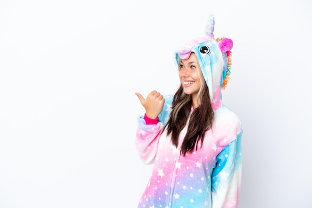 Jeune femme russe portant un pyjama licorne isolé sur fond blanc pointant vers le côté pour présenter un produit