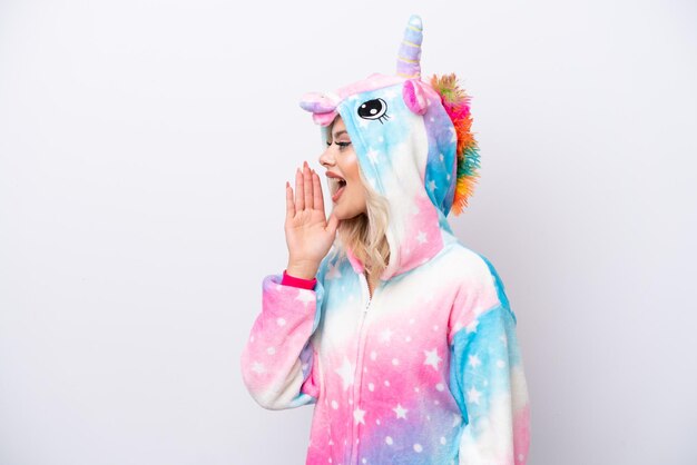 Jeune femme russe avec un pyjama licorne isolé sur fond blanc criant avec la bouche grande ouverte sur le côté