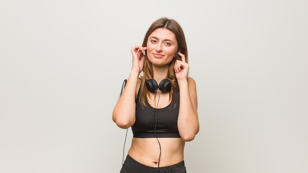 Jeune femme russe de remise en forme couvrant les oreilles avec les mains