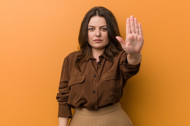 Jeune femme russe sinueuse debout avec la main tendue montrant le panneau d'arrêt