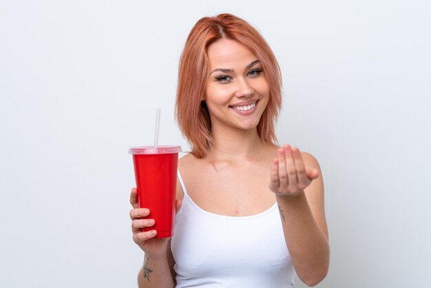 Jeune femme russe tenant une boisson gazeuse isolée sur fond blanc invitant à venir avec la main Heureux que vous soyez venu