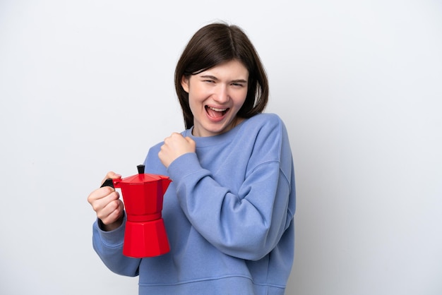 Jeune femme russe tenant une cafetière isolée sur fond blanc célébrant une victoire