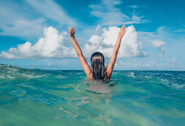 Jeune femme s'amuser et sauter à l'eau bleue de l'océan