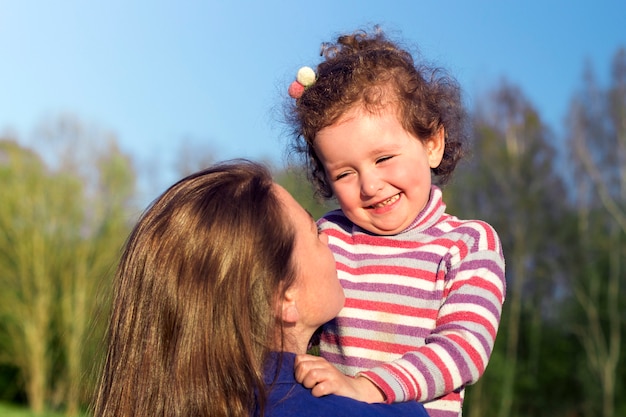 Jeune femme s'amuser, sourire avec sa mignonne petite fille enfant. Portrait de mère, petite fille enfant à l'extérieur à la journée ensoleillée d'été. Fête des mères, amour, bonheur, famille, parentalité, concept de l'enfance