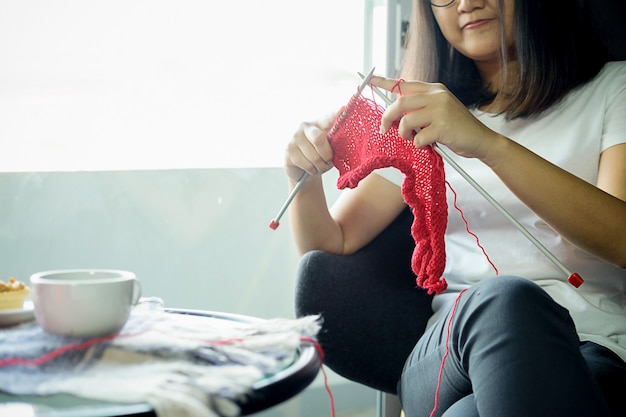 Jeune femme s&#39;assoit à la maison et tricote des vêtements.