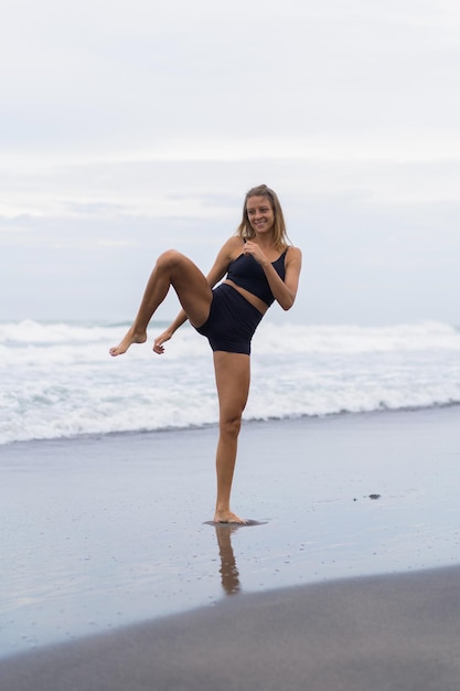 Jeune femme s'entraîne sur la plage, taekwondo, coups de pied, spinner, coup de pied circulaire.