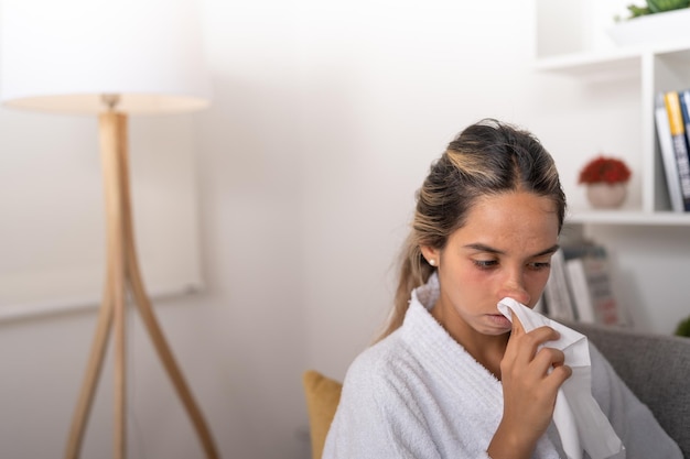Jeune femme s'essuyant le nez avec un morceau de tissu après avoir éternué