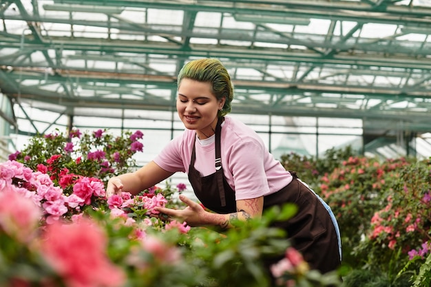 Une jeune femme s'occupe de fleurs colorées dans une maison verte vibrante remplie de vie et de beauté.
