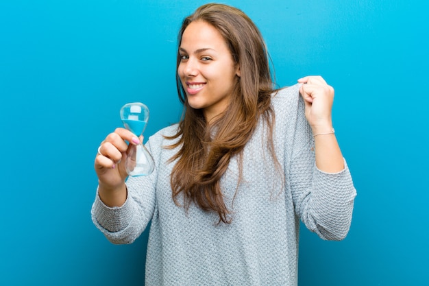 Jeune femme avec sablier sur fond bleu