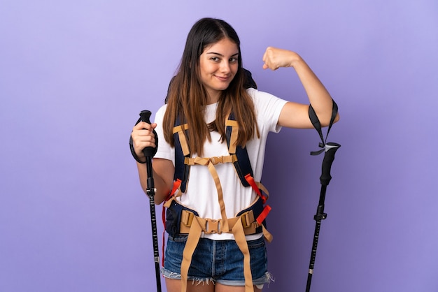 Jeune femme avec sac à dos et bâtons de randonnée violet faisant un geste fort