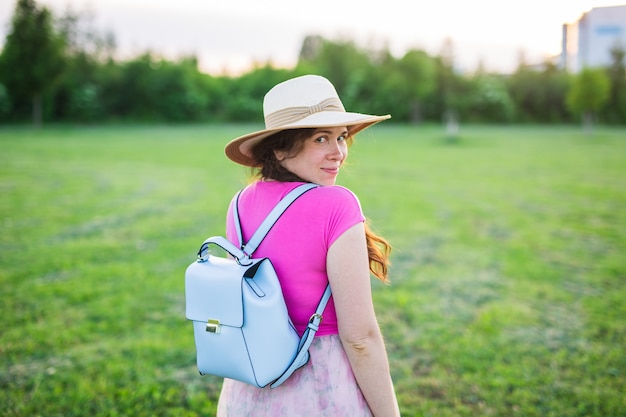 Jeune femme avec sac à dos bleu et chapeau profitant de la vue arrière de la campagne