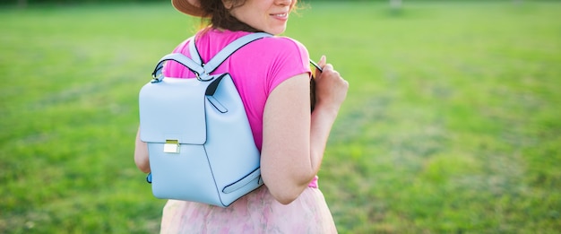 Jeune femme avec sac à dos bleu et chapeau profitant de la vue arrière de la campagne