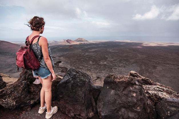 Jeune femme avec un sac à dos en contemplant la zone volcanique du parc naturel de Timanfaya à Lanzarote à Lanzarote